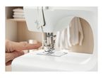 Close-up of a hand using the automatic needle threader on a white sewing machine.