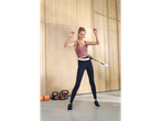 Mulher com sapatilhas desportivas Crivit e bambolê inteligente, com kettlebells e tapete de yoga.