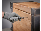 Luva de trabalho com chave de impacto Parkside inserindo um parafuso na madeira.