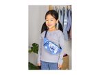 Smiling girl wearing a blue fanny pack with a cartoon character, standing in a room with clothes rack.