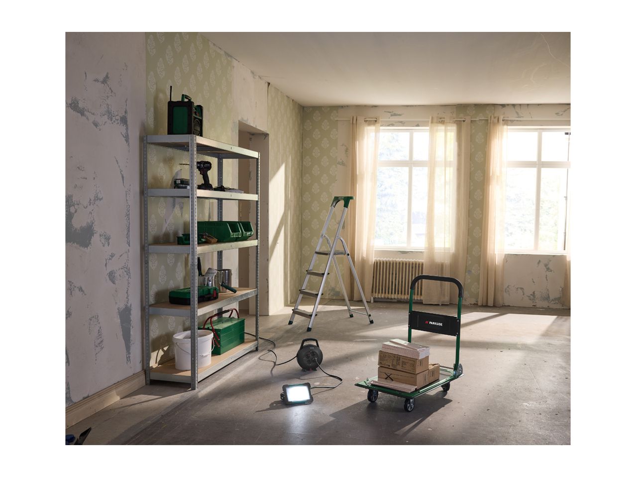 Room being renovated with a metal shelving unit, step ladder, and hand truck with boxes.