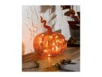 A glowing orange glass pumpkin with a curled stem on a wooden surface.