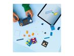 Child building a toy game console with colorful bricks, following instructions on a tablet.