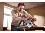 Man using a Parkside® 20V Cordless Circular Saw to cut wood, with sawdust in the air.