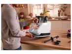 Man placing a food processor with a digital screen onto a kitchen counter.