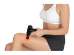 Woman in sports bra and shorts using a red light therapy massage gun on her knee.
