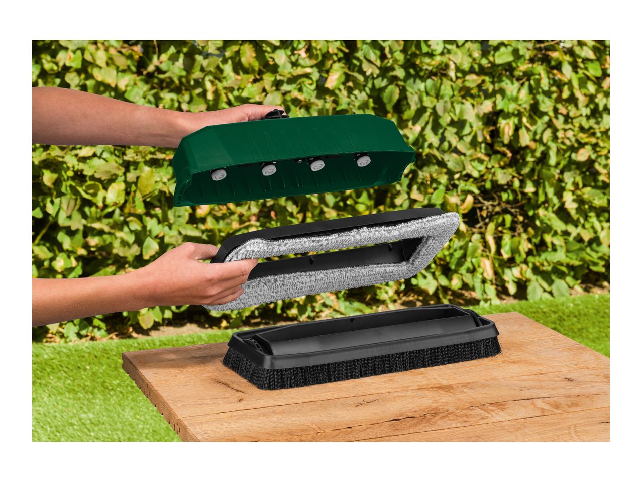 Person assembling a green garden sweeper with a brush and a microfiber pad.