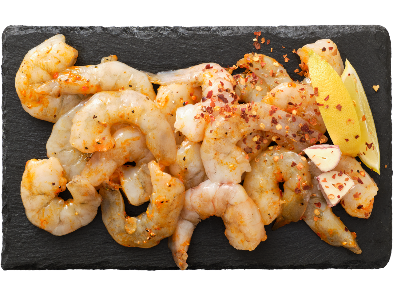 Žalios krevetės kario marinate su čili dribsniais, citrina ir česnaku ant tamsios skalūno plokštės.