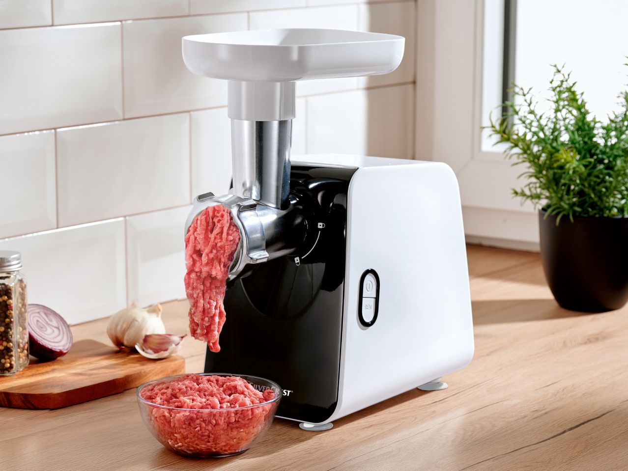 SilverCrest meat grinder processing meat, with onions, garlic, and spices on a wooden board.