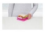 A person holding a sandwich in a pink lunchbox on a white table.