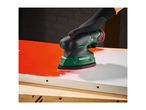 A person wearing a black glove uses a power sander on a red and white surface.