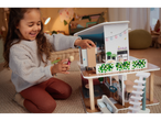 A smiling child plays with a Playtive Doll House, moving a doll inside.