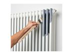 A hand painting a white radiator grey with a paintbrush.