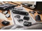 Hair trimmer set with various attachments, scissors, and oil on a wooden surface.