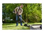Man using a petrol brush cutter to trim grass in a garden.