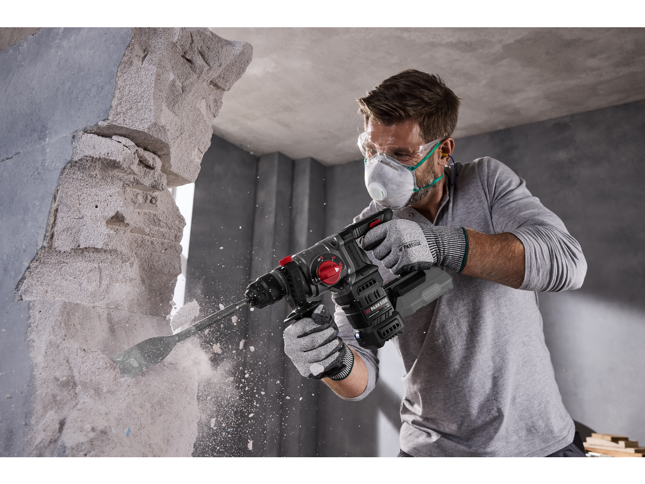 Man using a PARKSIDE PERFORMANCE® 20V Cordless Hammer Drill to break through a wall.