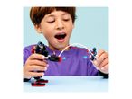 A boy playing with a black and red toy robot and a blue toy figure, launching a web.