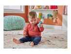 Baby playing with a colorful rattle on a patterned rug, with a teal pouf nearby.