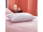A light lavender pillow sits on a pink bedsheet in a bedroom with coral walls.