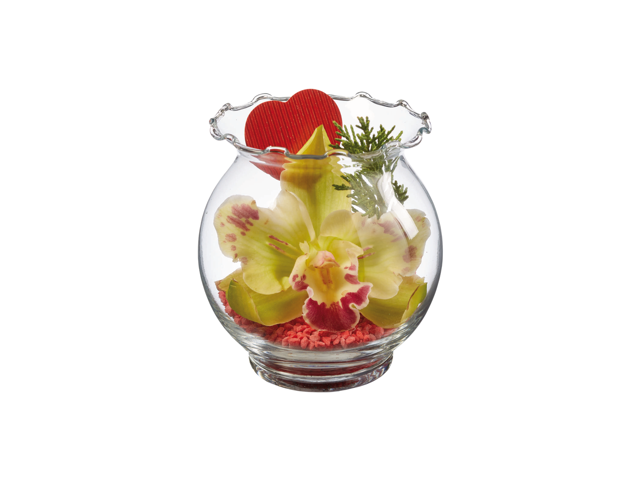 Glass vase with a yellow orchid, red heart, and green foliage on red pebbles.