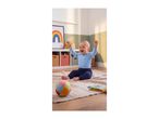 Happy baby in blue clothing sitting on a rug with a colorful ball and toy book.