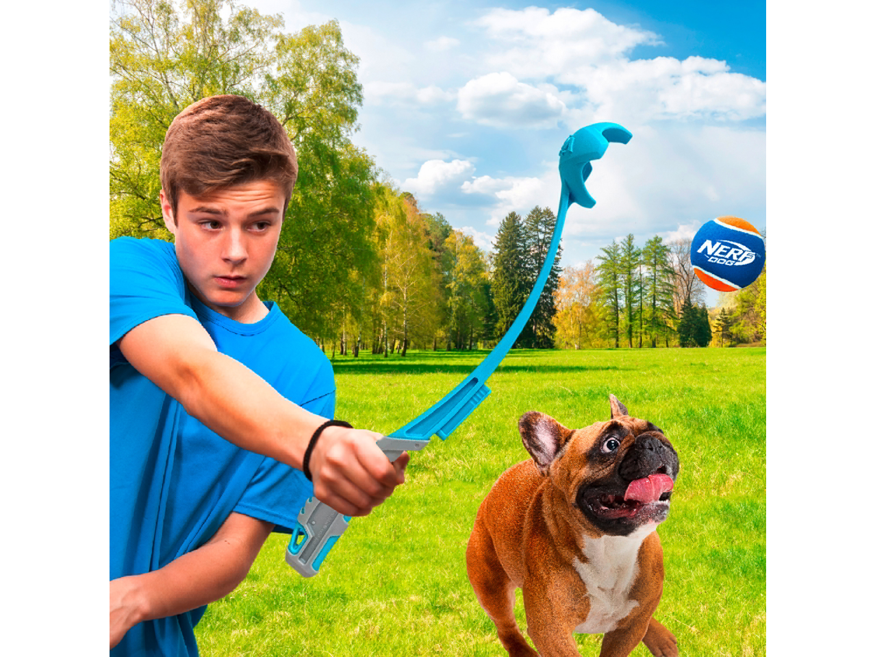 Boy launching a Nerf Dog tennis ball for a French Bulldog in a park.